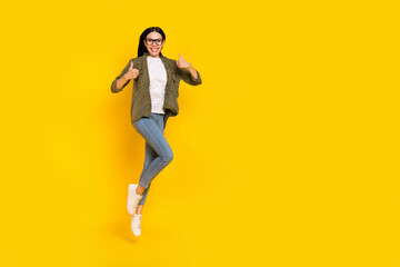Fototapeta na wymiar Full body photo of cool millennial lady jump thumb up wear eyewear shirt jeans footwear isolated on yellow background