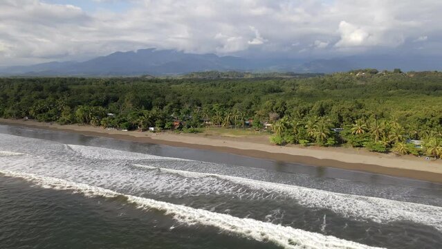 Long, sandy coastline of Playa Quepos on the tropical Isla Damas in Costa Rica. Descending aerial orbit