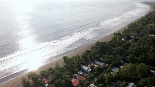 Red car driving on the long, sandy beach of Damas Island in Costa Rica's Province Puntarenas. Aerial tracking shot from high above.