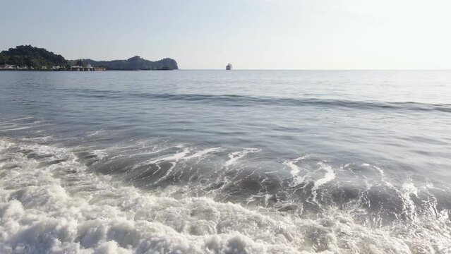 A long wave crashing ashore at the empty Quepos beach on Damas Island, Costa Rica. Aerial backwards tracking shot