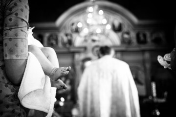 The sacrament of the baptism of a child in an Orthodox church, the priest anoints the baby's feet...
