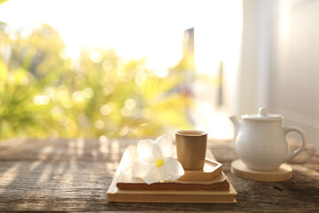 Tea cup and white tea pot and notebook with plumeria flower