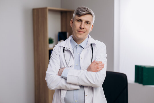 Portrait of male doctor physician in medical uniform. Friendly Family therapist standing with arms crossed looking at camera.