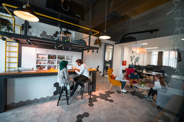 Group of casual multiethnic business people taking break from the work doing different things while enjoying free time in relaxation area at modern open plan startup office