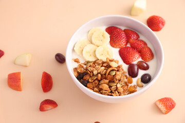 bowl of granola cereal with yogurt and berries isolated on eggnog color background