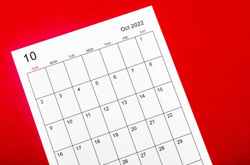 October 2022 calendar sheet on red background.