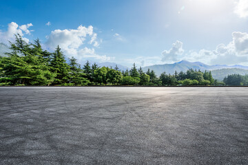 Empty asphalt road and green forest with mountain scenery under blue sky