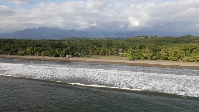 The long coastline of Playa Quepos on the tropical Isla Damas in Costa Rica. Slowly descending aerial orbit