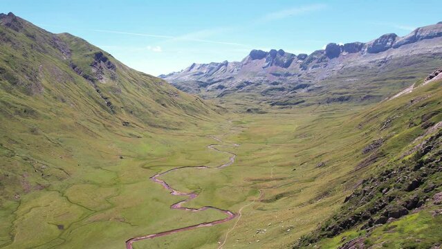 Large winding river between the huge barely vegetated mountains in the Valle de Hecho Y near Huesca in Spain on a hot summer day. aerial drone dolly shot