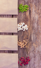 bean, pea, chickpea and pumpkin seeds in paper packets on a rustic wooden table, close-up top view. concept of farming, gardening, planting organic natural products.
