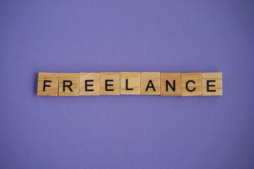 Word freelance. Wooden blocks with lettering on top of purple background. Very Peri background color 2022. Human Resource Management and Recruitment and Hiring concept.