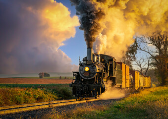 Obraz na płótnie Canvas A View of an Antique Freight Steam Train Blowing Smoke Approaching Thru Trees in Late Afternoon