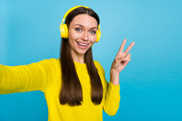 Photo of impressed millennial brunette lady listen music do selfie show v-sign wear shirt headphones isolated on blue background