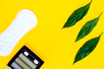 women's perfumes and cosmetics with plant leaves on a colored background  