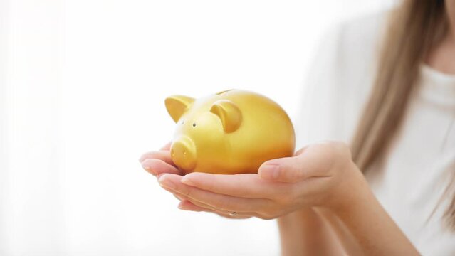 ブタの貯金箱を持つ若い女性