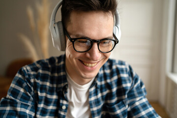 Fototapeta na wymiar Gamer adult male in wireless headphones and glasses, close portrait happy playing a game
