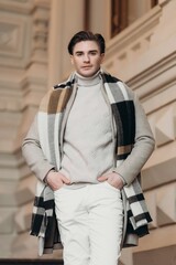  Young man wearing coat walking in the street. Young bearded guy with modern hairstyle in urban background