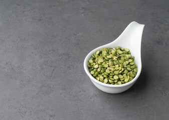 Raw dried green peas in a bowl over stone background with copy space