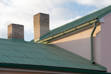 Metal Roof green painted, Steel Materials Coated Private House Roof with chimneys. Building Materials Roof Drainage system