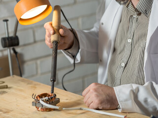 a man soldering iron solders a part from an electrical appliance. the concept of repair of equipment