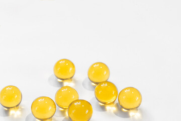 Yellow round capsules with fish oil for nutrition omega diet health benefits close-up on a white background with copy space