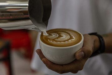 cup of coffee latte art in barista hand.