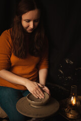 woman makes plate of clay in pottery workshop, smiles, happy, beautiful, background, authentic atmosphere, lifestyle. yellow lamp