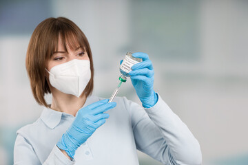 female doctor or nurse wearing face mask and medical gloves is handling syringe with coronavirus...