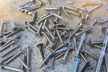 Self-tapping screws of various sizes are placed on the cement floor.