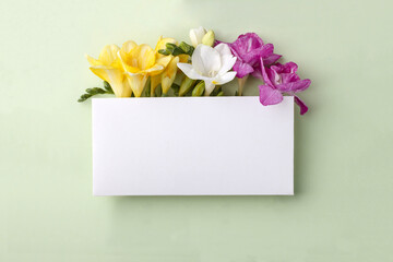 Mockup with blank rectangular sheet of paper and colorful freesia flowers with copy space.