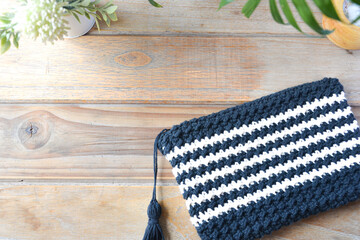 crocheted toiletry bag on wooden background with plants and candle