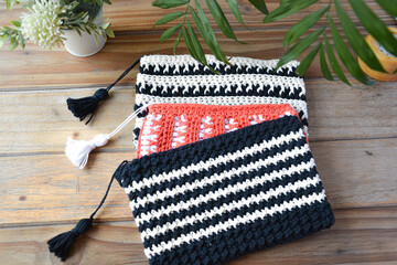 crocheted toiletry bag on wooden background with plants and candle