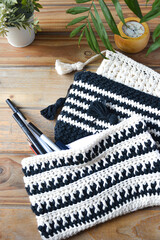 crocheted toiletry bag on wooden background with plants and candle