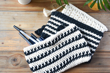 crocheted toiletry bag on wooden background with plants and candle