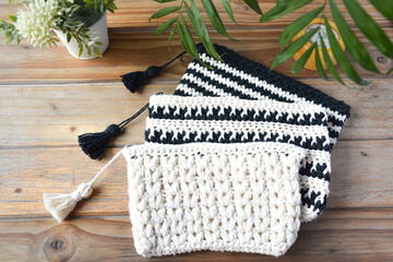 crocheted toiletry bag on wooden background with plants and candle