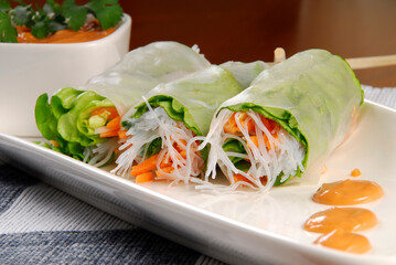 Vietnamese rolls with vegetables, rice paper roll with vegetables and chipotle chili dressing on a wooden table