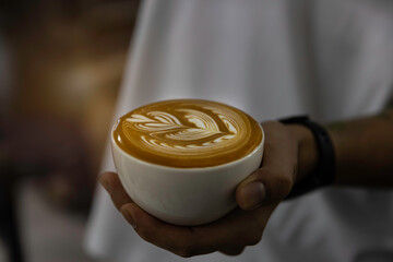 cup of coffee latte art in barista hand.