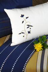 Blue and white striped embroidered cushions and fabrics on gold tone stool adorned with yellow flower and space for text