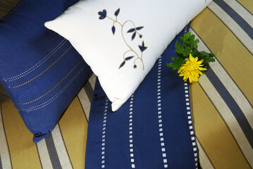 Blue and white striped embroidered cushions and fabrics on gold tone stool adorned with yellow flower and space for text