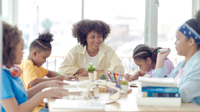 A group of four young African students studying with an African female teacher in a classroom at the school where everyone is studying very hard. This picture is an educational concept.