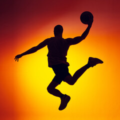 Silhouette of basketball player in motion, action isolated on gradient yellow orange background in neon light. Sport, diversity, activity concepts.