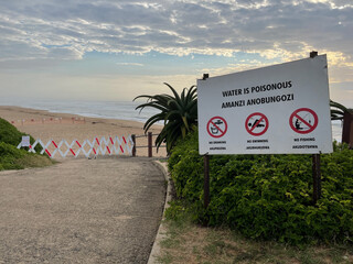 Medium shot of hazardous area sign and barricade stretched across entrance of beach at Umhlanga,...