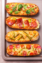 Slices of Pizza on bread with cheese and ingredients such as salami, prosciutto, ham. Flat lay, rustic style