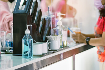 Blue alcohol gel bottle for hand cleaning to prevent the spreading of the Coronavirus (Covid-19) on counter to service for customers at cafe or coffee shop. Healthcare concept. New normal lifestyle.