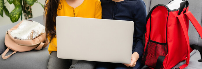 Two cute child girls using laptop together with fun and happiness