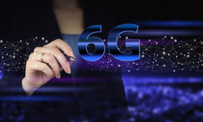 The concept of 6G network, high-speed mobile Internet, new generation networks. Hand holding digital graphic pen and drawing digital hologram 6G sign on city dark blurred background.