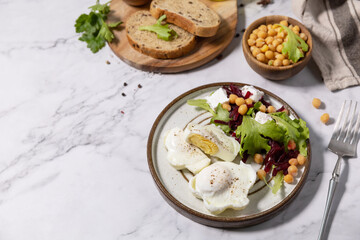 Easter breakfast or brunch. Poached egg and beet salad with spinach, cheese feta, chickpeas on a marble tabletop. Copy space.