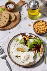 Easter breakfast or brunch. Poached egg and beet salad with spinach, cheese feta, chickpeas on a marble tabletop.