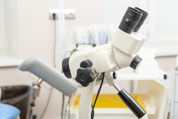 Colposcope closeup on the background of gynecological chair.