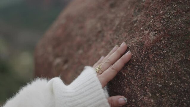 Crop woman touching stone in nature